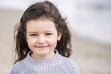 closeup view portrait of cute calm pretty white smiling happy little girl with long brown hair stand
