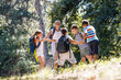 © BalanceFormCreative - Group of kids relaxing in the nature with the teacher. They're spinning around and having fun.