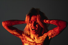Aggressive Woman. Silhouette Portrait. Bipolar Disorder. Depression Stress. Panic Despair. Screaming Female Holding Head With Pressure Isolated On Dark Red Shadow Light Double Exposure.