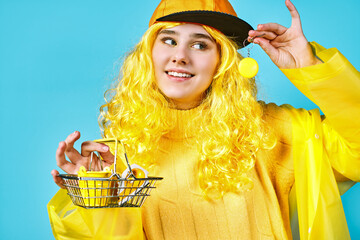 cute teenage girl in yellow cap with small shopping basket. concept. blue background