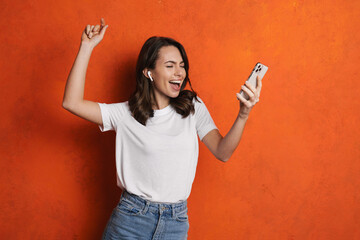 Sticker - Happy girl in earphones singing and dancing while using cellphone