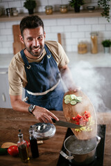 Wall Mural - Handsome man preparing pasta in the kitchen. Guy cooking a tasty meal..