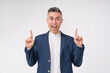 Excited middle-aged businessman pointing at copy space isolated over white background
