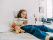 © Albert Morcillo/ADDICTIVE STOCK - Smiling glad little girl wearing casual clothes lying on comfortable bed and watching video on modern tablet in light bedroom