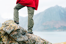Back View Anonymous Traveler In Warm Clothes Standing On Massive Rock And Admiring Scenic Mountain Range Surrounding Tranquil Lake On Autumn Day