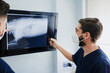 © Alberto Ortega/ADDICTIVE STOCK - Anonymous male vet in respiratory mask and uniform explaining anatomy of mammal animal while touching screen with X ray illustration in clinic