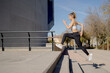 © Alvaro Atalaya/ADDICTIVE STOCK - Full body side view of energetic young fit female in sportswear running fast upstairs during fitness workout on urban street
