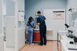 © Alberto Ortega/ADDICTIVE STOCK - Unrecognizable young male vet in sterile mask and gloves standing near female colleague while preparing for work in lab