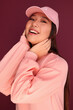 © Victor Torres/ADDICTIVE STOCK - Portrait of happy young asian woman in the studio wearing pink clothes over garnet background