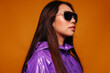 © Victor Torres/ADDICTIVE STOCK - Portrait of Asian young woman with serious expression. She wears a purple jacket and a black sunglasses and is looking away against a yellow background
