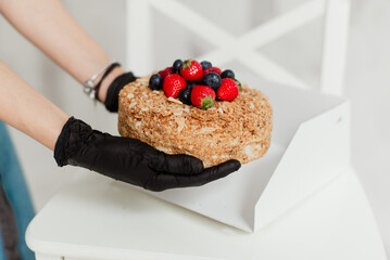 pastry chef girl in black gloves holding honey cake