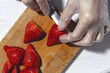 © Eduardo Lopez/ADDICTIVE STOCK - Top view crop unrecognizable chef in latex gloves cutting fresh delicious strawberries on wooden cutting board on table
