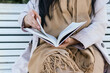 © David Munoz/ADDICTIVE STOCK - Cropped unrecognizable female reading book sitting in bench