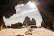 © Francisco Carrodeguas/ADDICTIVE STOCK - Back view of unrecognizable female in casual clothes and hat standing on sand in entrance of cave near sea looking at a bird in Algarve, Portugal