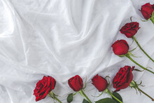 Top View Composition Of Blooming Fresh Red Rose Flowers Arranged On White Cloth With Blank Space