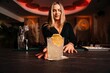 © Gustavo Pozo/ADDICTIVE STOCK - Content young female bartender with long blond hair serving cold alcohol cocktail decorated with lemon slice in stylish restaurant