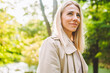 © Olga Rolencino - Caucasian blonde woman smiling happily on sunny summer or spring day outside walking in park.