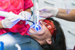 © Ioritz Lopez/ADDICTIVE STOCK - Crop anonymous dentist in gloves using dental ultraviolet curing light tool during procedure with patient in clinic