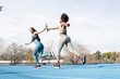 © Jose Carlos Cerdeno/ADDICTIVE STOCK - Fit multiracial female athletes passing baton while running along track at stadium during relay race