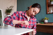 © Juan Alberto Ruiz/ADDICTIVE STOCK - Ethnic Asian female sitting on floor and screwing wooden board while assembling new furniture at home