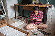 © Juan Alberto Ruiz/ADDICTIVE STOCK - From above ethnic Asian female sitting on floor and screwing screws in wooden board while assembling new furniture at home