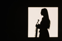 Side View Silhouette Female Violinist Standing With Musical Instrument And Thoughtfully Looking Away