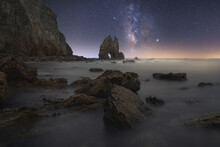 Amazing Scenery Of Sea Coast With Calm Water And Rocky Cliffs With Caves Under Dark Sky With Milky Way