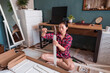 © Juan Alberto Ruiz/ADDICTIVE STOCK - High angle of focused ethnic female using hammer for nailing wooden dowels while assembling new furniture in apartment