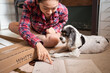 © Juan Alberto Ruiz/ADDICTIVE STOCK - Smiling Asian female sitting on floor with fluffy dog and reading instruction while assembling furniture in new apartment