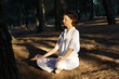 © Marianna Jaszczuk/ADDICTIVE STOCK - Side view of calm barefooted adult female in casual clothes meditating with closed eyes in Lotus asana while sitting on ground in forest on sunny day and practicing yoga