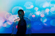 © Luis Manuel Munoz/ADDICTIVE STOCK - African American woman in trendy fur coat standing under vivid blue projection with specks of light