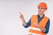Cheerful caucasian construction worker pointing at copy space isolated over white background