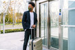 © Luis Manuel Munoz/ADDICTIVE STOCK - African American male tourist with suitcase and in protective mask standing near of elevator in airport while traveling during coronavirus pandemic