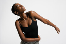 Slender Black Woman In Casual Clothes Dancing With Closed Eyes Against Gray Background