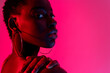 © Luis Manuel Munoz/ADDICTIVE STOCK - Portrait of self assured young African American female model in black top looking over the shoulder while standing against pink background in neon light