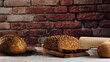 © Luis Mario Hernandez/ADDICTIVE STOCK - White and rye bread with cereals and appetizing crust on cutting board against brick wall in bakehouse