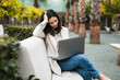 © Luis Tenza/ADDICTIVE STOCK - Pensive female entrepreneur using laptop while sitting on bench in city park and working online on project