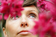 © Marianna Jaszczuk/ADDICTIVE STOCK - Crop pensive adult female with short hair recreating in green garden near bright blossoming flowers and looking up