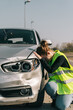 © Older Garcia/ADDICTIVE STOCK - Side view of suffered young female driver in casual clothes and road safety vest leaning head on damaged car hood after accident on road on sunny day