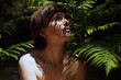 © Marianna Jaszczuk/ADDICTIVE STOCK - Alluring young naked woman with dark hair sitting near fern bush in lush tropical forest and looking up on sunny day