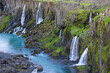© PACO FARERO/ADDICTIVE STOCK - Spectacular view of rapid cascades flowing from rough rocky cliff covered with lush greenery into tranquil blue reservoir in peaceful nature