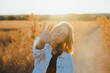 © Miguel Palomo/ADDICTIVE STOCK - Front view of active young lady in trendy outfit showing hand in dry fiends against cloudless sky in countryside