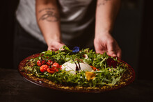 Hands Of Anonymous Person Holding A Yummy Burrata Cheese On Cold Tomato Cream With Arugula Leaves And Cherry Tomatoes With Truffles And Peanuts
