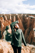 © Nacho Zaitsev/ADDICTIVE STOCK - Young cheerful female tourist in warm clothes and eyeglasses standing against gorge with eyes closed under cloudy sky in Spain
