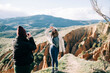 © Nacho Zaitsev/ADDICTIVE STOCK - Unrecognizable female tourist taking photo of glad best friend on camera against mount and canyon in sunlight