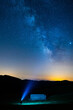 © Pol Sole/ADDICTIVE STOCK - Anonymous traveler silhouette with blue light standing near mountain under colorful sky with stars at night
