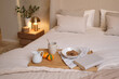 © Philippe Degroote/ADDICTIVE STOCK - Food and drink on wooden tray with book placed on comfortable bed in modern cozy bedroom for breakfast