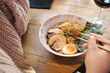 © Philippe Degroote/ADDICTIVE STOCK - High angle side view of crop unrecognizable female with chopsticks eating delicious Asian ramen with pork and boiled egg