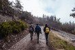 © Ruben Soto/ADDICTIVE STOCK - Back view of anonymous trekkers with rucksacks strolling on walkway near mount with trees under cloudy sky