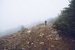 © Ruben Soto/ADDICTIVE STOCK - White dog and male owner walking on rough rocky slope in highlands on foggy day